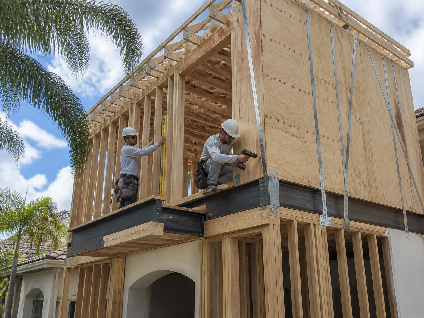 Carpenters framing a second-story home addition with hurricane strapping on an upscale Boca Raton residence